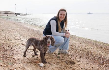 Emily Heaslip kneels next to her dog on the beach at Felixstowe
