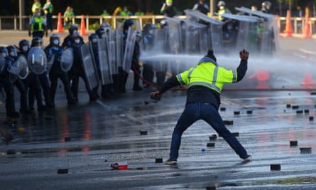 A protester throws cobblestones at police.