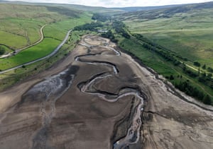 The dry bed of a reservoir with just a small stream flowing through it