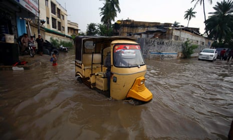 A vehicle makes its way through a flooded area, water covering its wheels, after heavy rains in Karachi, Sindh province, Pakistan.