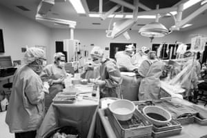 A wider image of the activity throughout the liver transplant surgery. Theatre staff are surrounding the table on the left, which has the sterilised instruments, with the table on the right for used equipment.