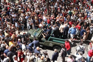 People surround a military vehicle as it parades during the ceremony