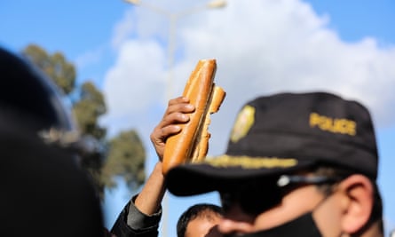 A protest holds up bread at an anti-government demonstration in Tunis. The country’s political upheavals have added to its debt woes.