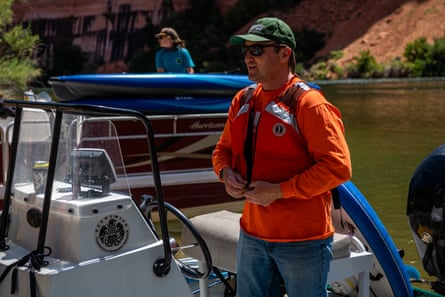 man in orange jacket next to boat