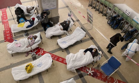 Covid patients lie on hospital beds in the lobby of a Chinese hospital