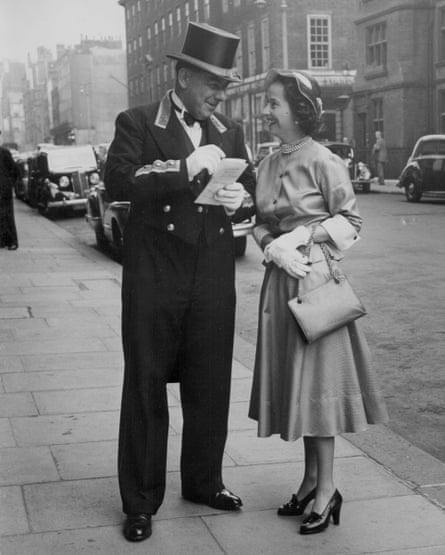 Una mujer sonríe mientras habla con un hombre con sombrero y uniforme.