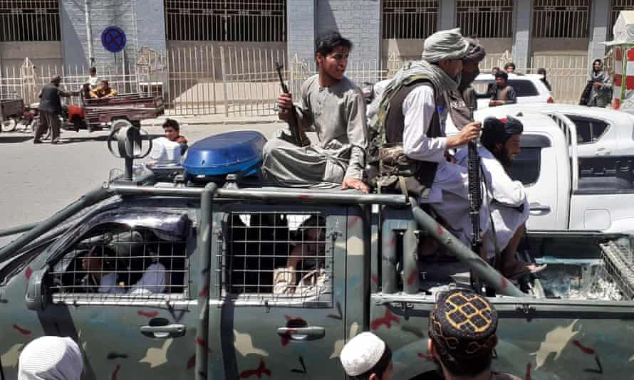 Taliban fighters drive through Kandahar in a captured military vehicle
