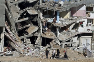 Shejaiya, 2014 A Palestinian family walks past the collapsed remains of a building