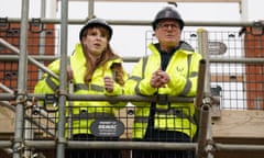 Keir Starmer and Angela Rayner dressed  in hi-vis vests standing on scaffolding at a building site