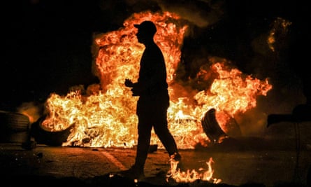 A man walks past flaming tires during clashes between Palestinian protesters and Israeli forces at the northern entrance of the city of Ramallah in the occupied West Bank.