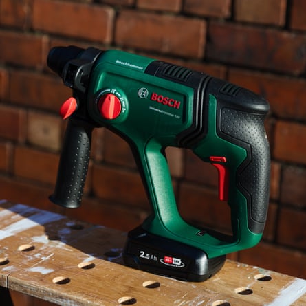 The Bosch UniversalHammer 18V on a wooden work bench in the sunlight against a red brick wall.