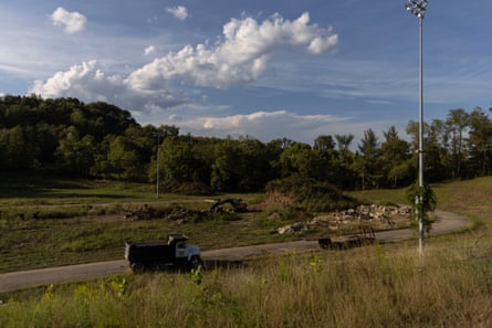 An open field with some remnants of rubble by the side of a road, while a truck drives by
