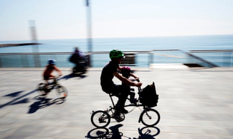 A man rides a bicycle with a child on a seaside promenade in Barcelona as children under the age of 14 are allowed to leave their homes for the first time in weeks.