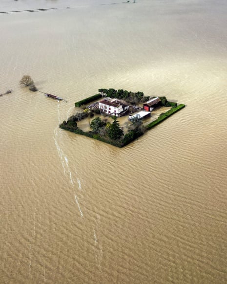 Aerial view shows an isolated house encircled by dirty water