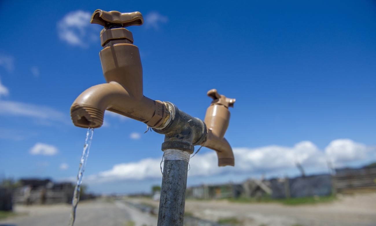 A communal tap runs as people collect water in a settlement near Cape Town, South Africa. On 11 May, the city is due to be the first in the world to turn off the water taps.