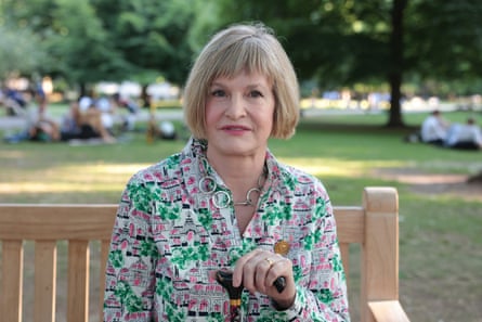 Portrtat of Pamela Fisher sitting on a park bench holding a walking a walking stick