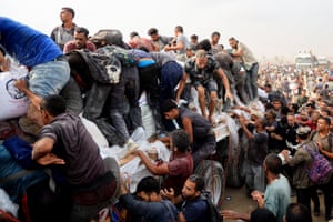 People climb aboard trucks full of aid in Khan Younis