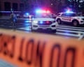 police cars with red and blue lights on are stopped behind police tape as a National Guard officer stands guard