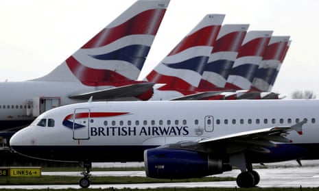 A British Airways plane taxis past tail fins of parked aircraft at Heathrow