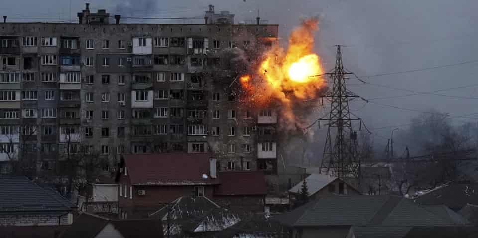 An explosion tears a hole in the side of an apartment building after a Russian tank fired a rocket in Mariupol in March.