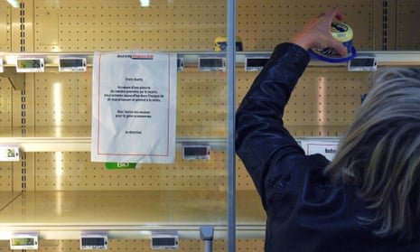 A woman grabs the last pack of butter from an empty refrigerated supermarket shelf