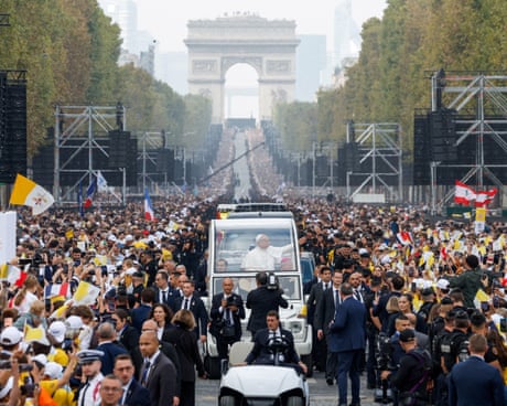 Pope Leo waves from the popemobile through a huge crowd, with the Arc de Triomphe in the distance