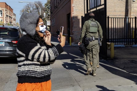 a person holds up a phone in the direction of a person in tactical gear