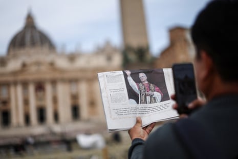 A man takes a photo of Vatican newspaper L'Osservatore Romano with St Peter's Basilica in the background, 9 May.