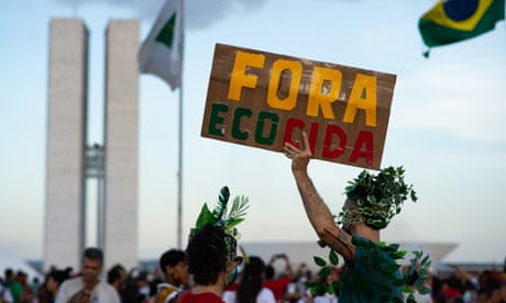 A man holds a sign that reads ‘Fora Ecocida’ (ecocide out) during an environmental protest against former president Jair Bolsonaro in Brasilia, Brazil, April 2022