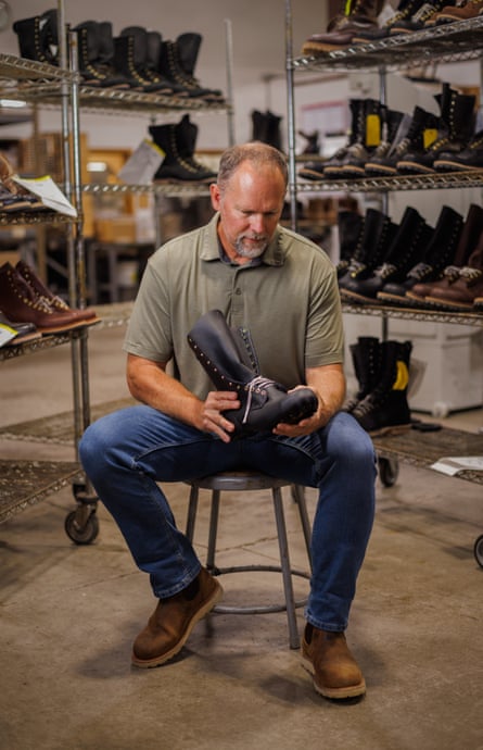 A man with a white goatee sits on a stool examining a boot.