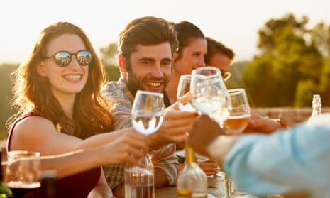 Group of friends toasting and laughing while having dinner outside