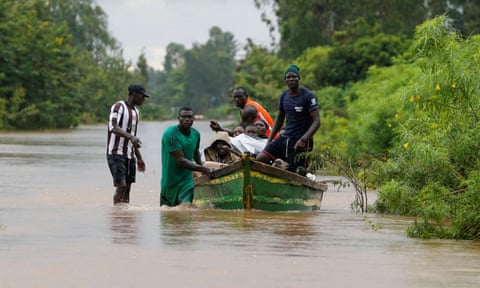 People using a boat to evacuate their village, near Lake Victoria, after flooding in May 2020. 