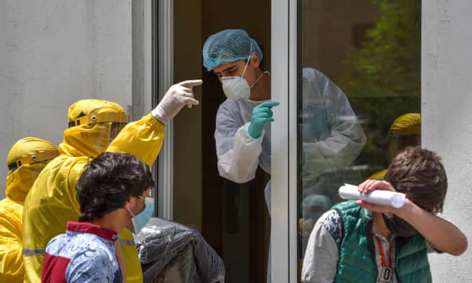 A hospital worker (C) wearing a protective face mask and outfit, speaks with two ambulance doctors wearing yellow protective suits at the Grigor Lusavorich Medical Centre in Yerevan amid the COVID-19 pandemic. 