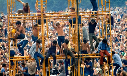 Woodstock festival, New York: August 1969. Crowd and people sitting on the sound tower.