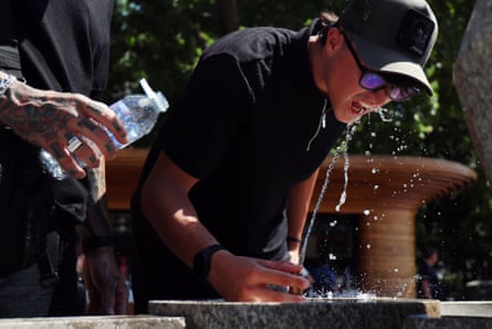 A man drinks from a fountain at a park in London.