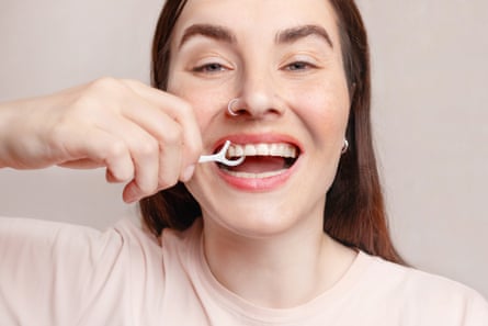 A woman uses dental floss on a stick