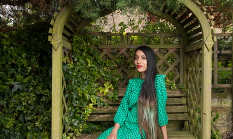 Yasmina Floyer in an arched garden seat in her garden at her home in Enfield, London
