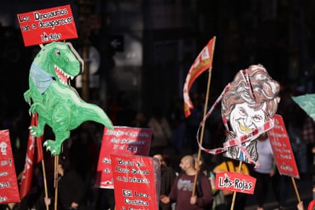 Banners held aloft show a caricature or Javier Milei and a dinosaur