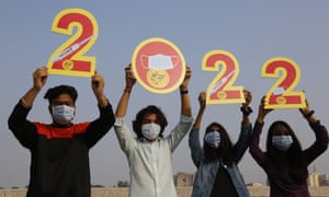 Usando máscaras faciales para ayudar a frenar la propagación del coronavirus, un grupo de personas en Ahmedabad, India, sostiene recortes para dar la bienvenida al 2022.