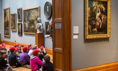 Schoolchildren, wearing red caps, sitting on the floor in the National Portrait Gallery, London