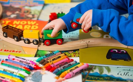 A child playing with a toy train amid books and colouring pens