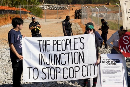 Protesters at the Cop City site holding up a sign reading 'the people's injunction to stop cop city'