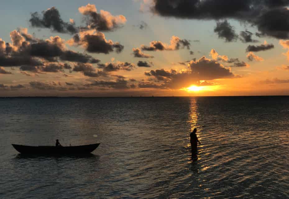 A fisherman returns home at dusk on his traditional wooden outrigger near the village of Ambo on South Tarawa.