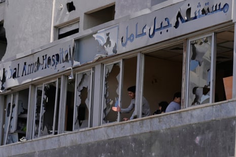 A man looks through the shattered windows of the damaged hospital.
