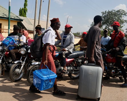 People with luggage and motorbikes leaving a school site