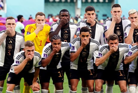 German players cover their mouths as they pose for a team group ahead of their opening match with Japan.