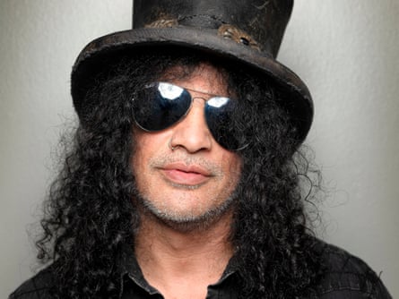 a man with long frizzy hair and a top hat and sunglasses looks to the camera