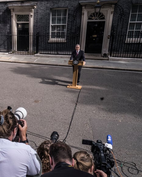A crowd of photographers and camera operators films Starmer speaking at a Downing St lectern