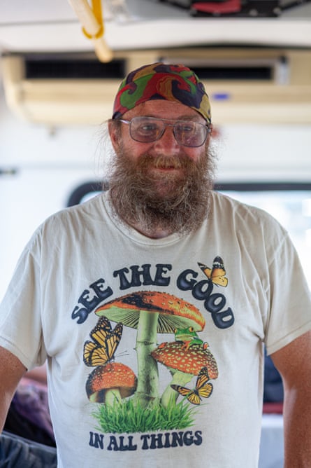 A man wearing a bandana and a shirt that says ‘see the good in all things’