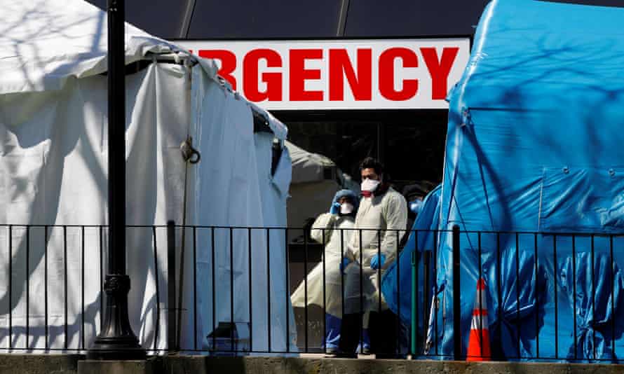 Health care workers stand outside a tent erected to test people for the Covid-19 at the Elmhurst Hospital Center in Queens, New York City.